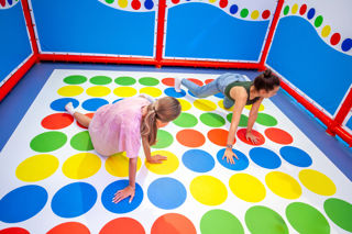 An image of two girls playing a game of giant twister in an indoor play centre